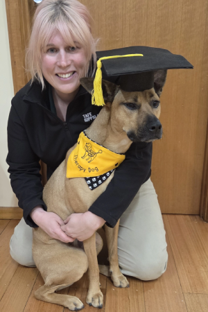 Kimberley with Norah in a graduate's cap after completing therapy dog training course