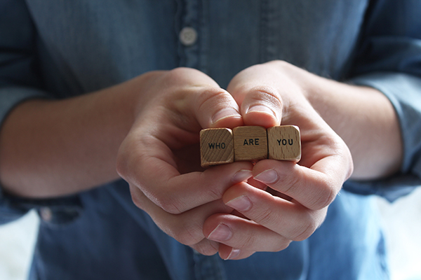 "Who are you" printed on wooden cubes held in a person's hands
