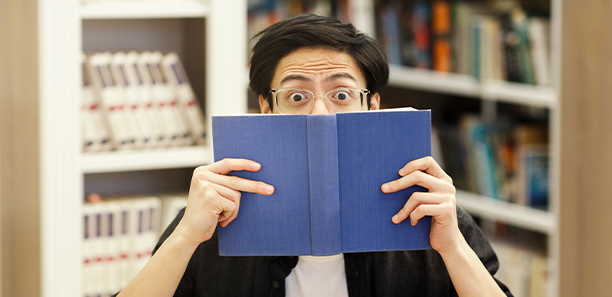 Young student peering over book