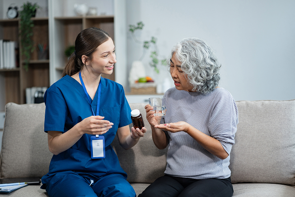 Aged care worker helping elderly patient take medicine