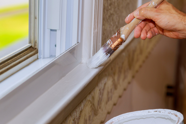 Painter using a brush on a window frame