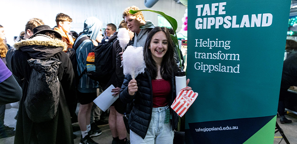 Young female student standing next to TAFE Gippsland banner