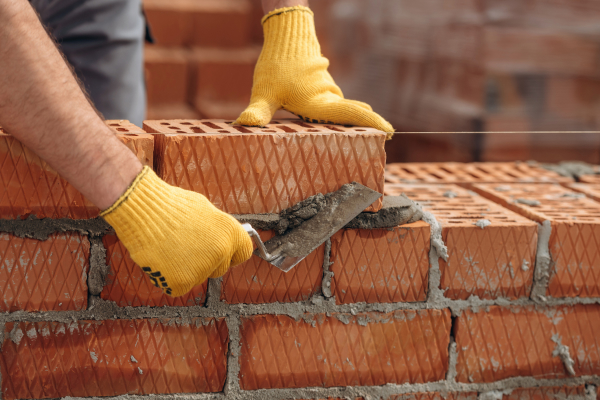 Bricklayer adding next brick in wall