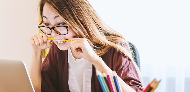 woman at laptop biting pencil 