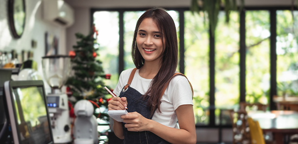 Young female cafe worker smiling at camera