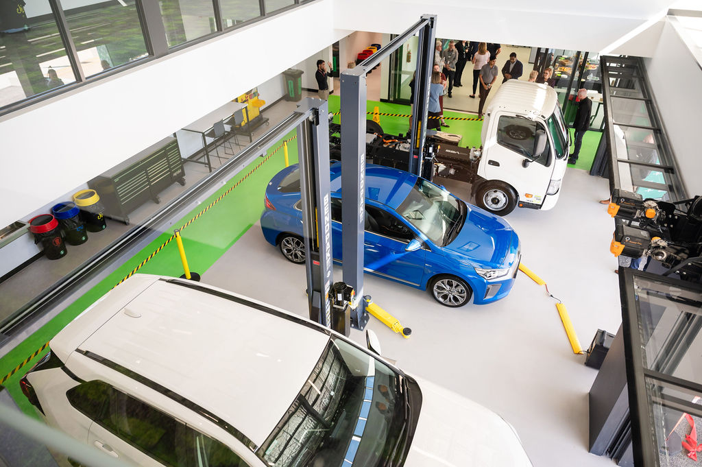 Electric and hybrid vehicles positioned on hoists in a modern training workshop